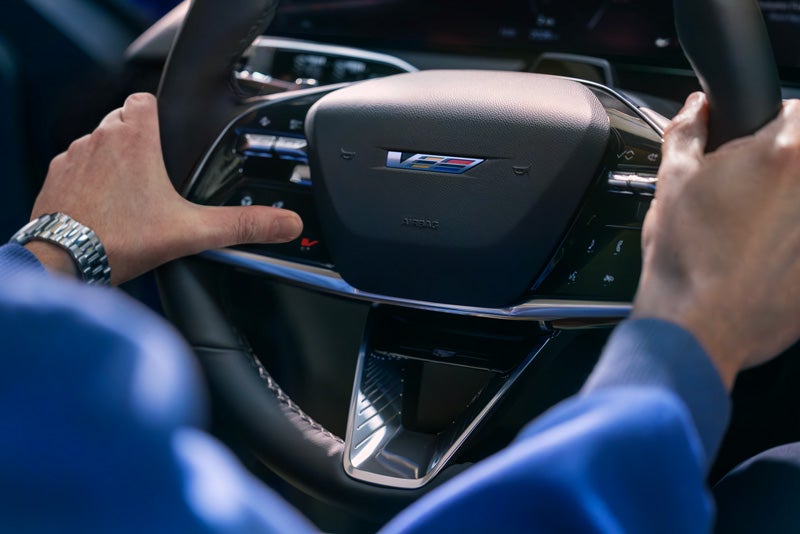Close-up of a Man About to Press the V-Button on the 2026 OPTIQ-V Steering Wheel | Joseph Cadillac in Florence KY