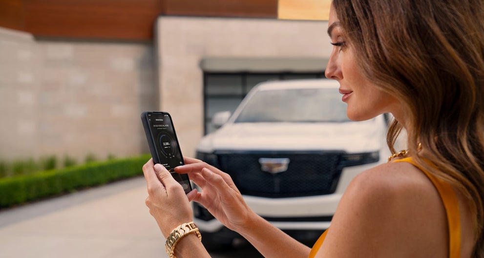 lady checking her mobile with a Cadillac vehicle background | Joseph Cadillac in Florence KY